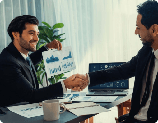 Two business professionals shaking hands over financial reports