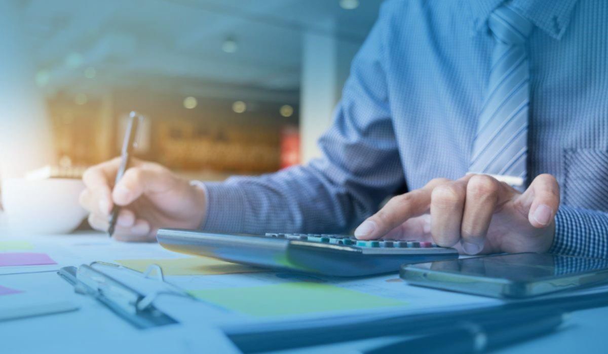 Tax professional using a calculator and reviewing documents at a desk